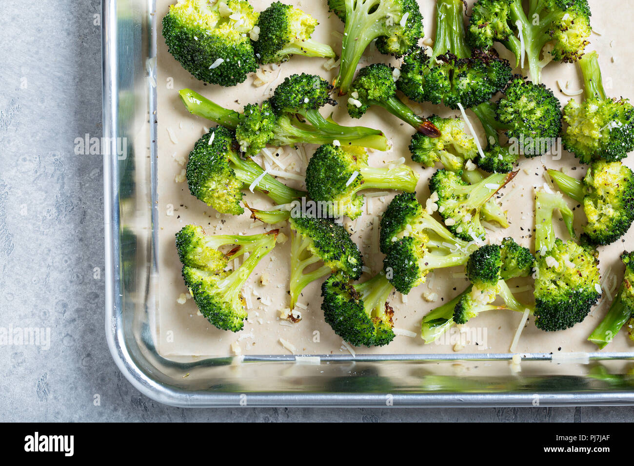 Roasted broccoli florets with cheese on a baking tray Stock Photo