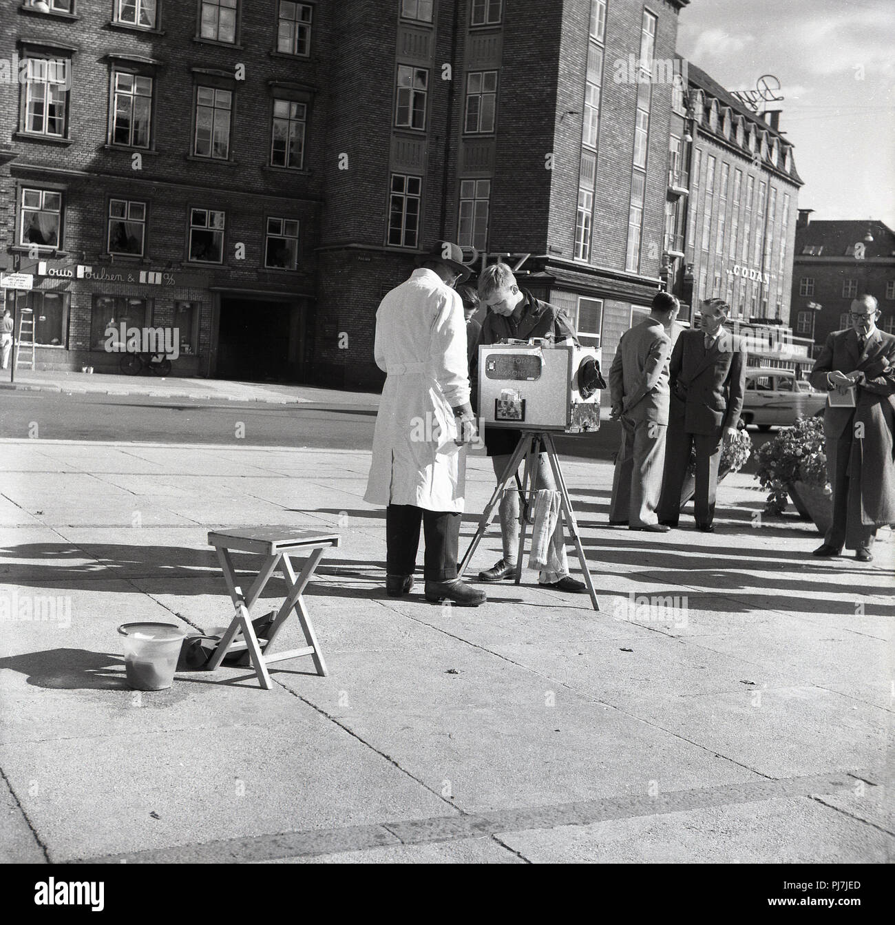 1950s, man in white coar with his mobile PA5 foto developer on a tripod outside on a pavement in Copenhagen, Denmark. price for developing the photos, 3 kroner. Stock Photo