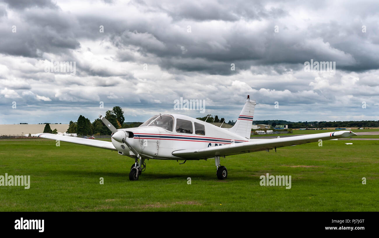 A single engine aircraft sits on the grass airfield Stock Photo