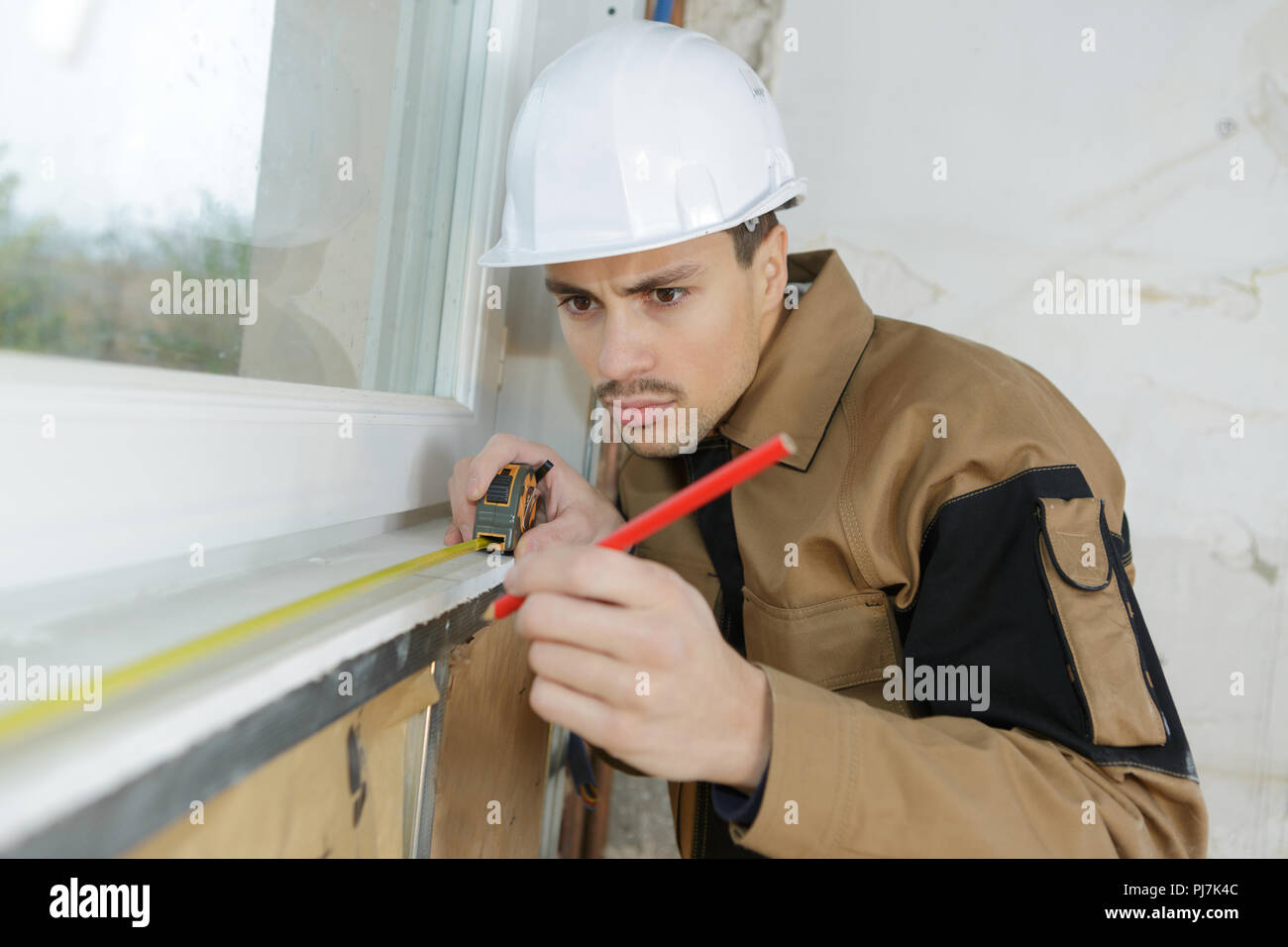 builder measuring the window pane Stock Photo Alamy