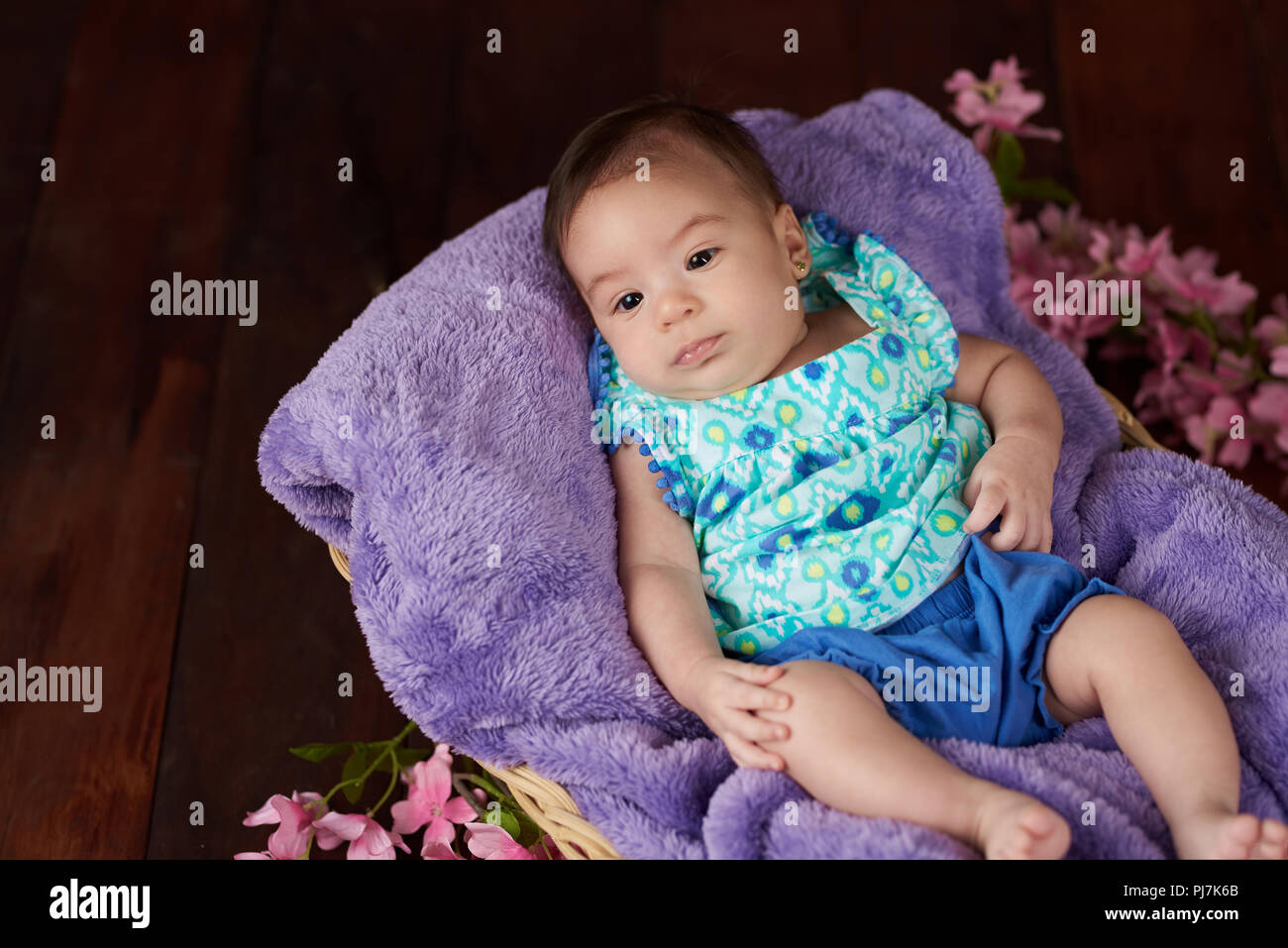 Portrait of cute baby girl on dark wooden studio background with copy space Stock Photo
