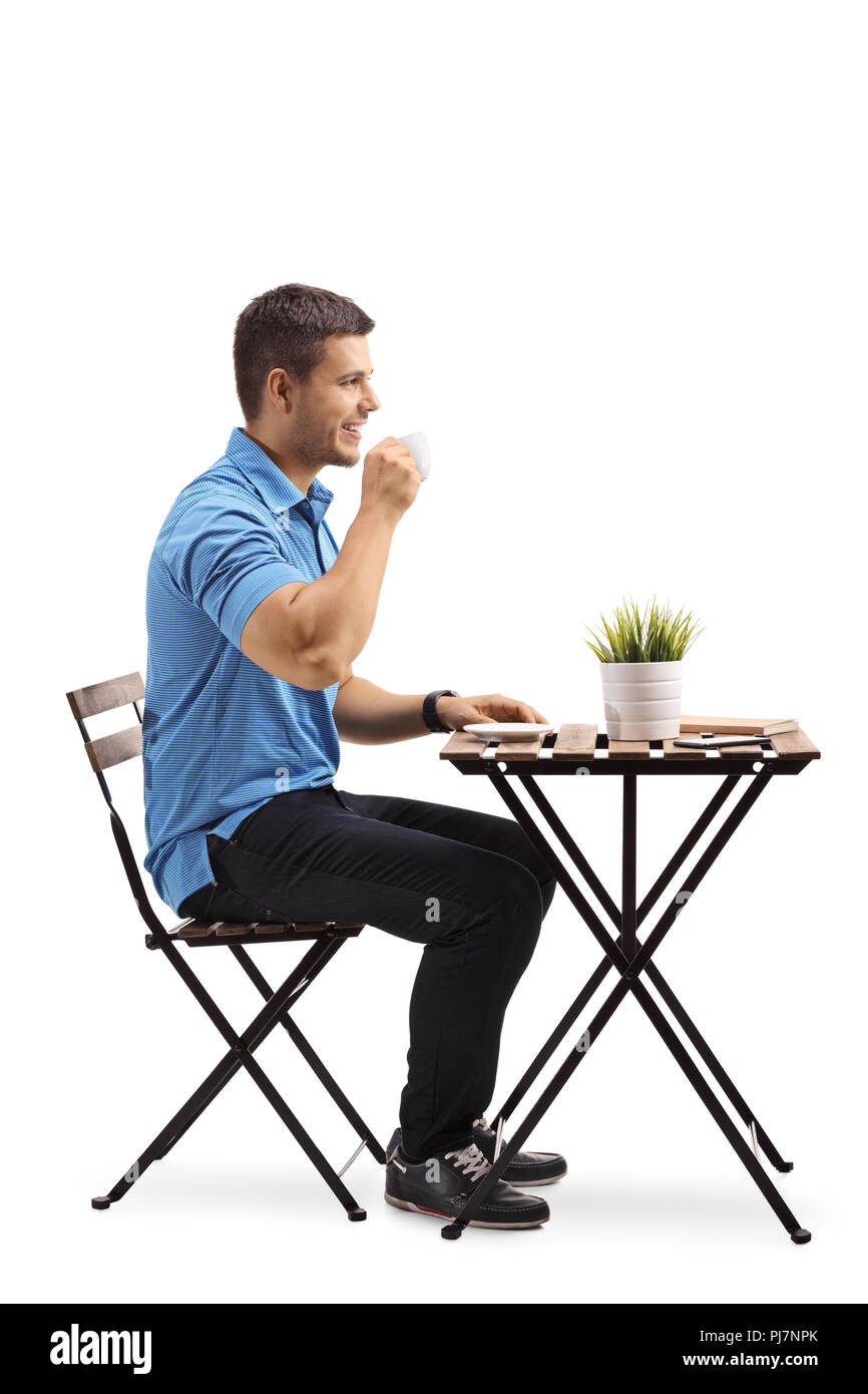 Young man drinking coffee and sitting at a table isolated on white background Stock Photo