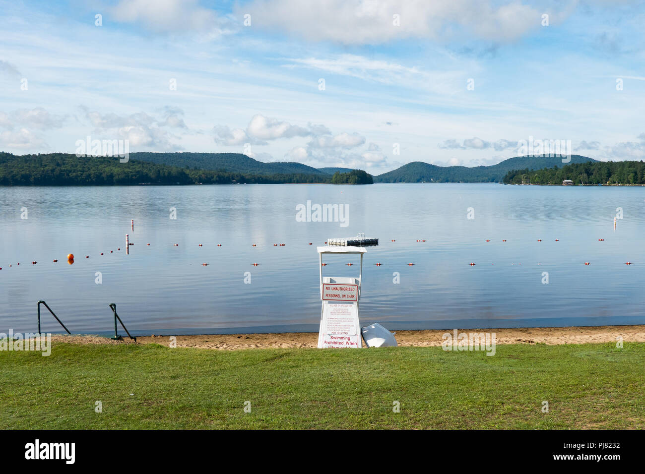 Speculator Village Beach on Lake Pleasant in the Adirondack Mountains with a floating raft,  lifeguard chair and rescue boat. Stock Photo