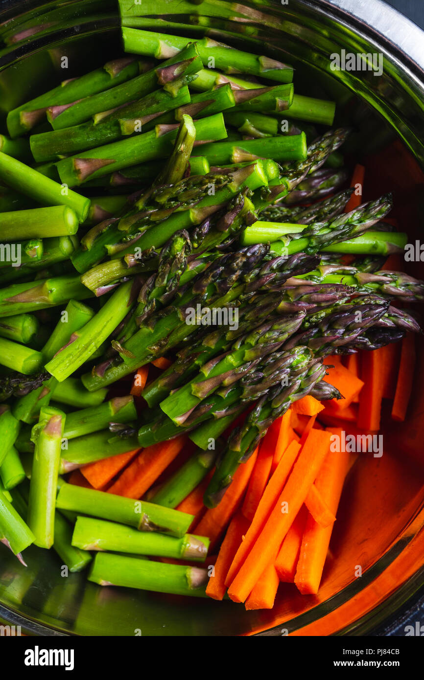Bowl of carrots and asparagus cut and prepared for a stir fry Stock