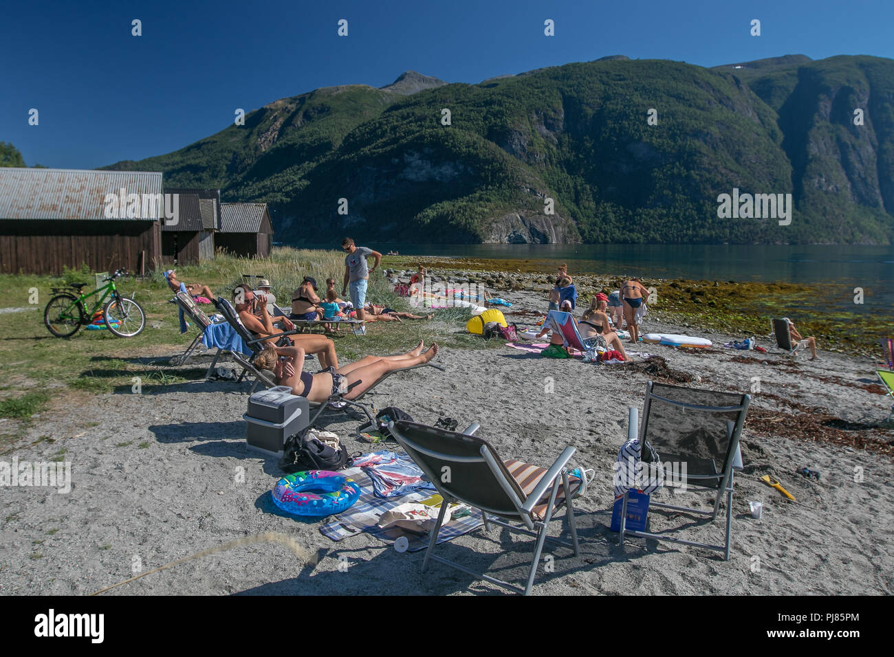 Norway, July 26, 2018: People are sunbathing on a fjord beach on a hot summer day. Stock Photo