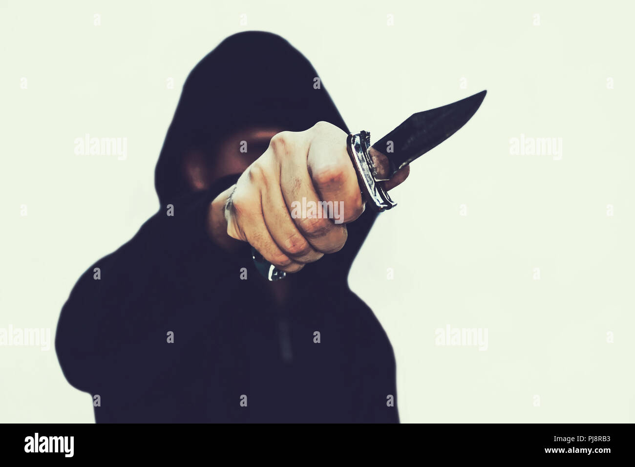 photo of a hooded man with a knife. A prisoner with a Shiv. The threat of a cold weapon. A terrorist from ISIS on a white isolated background Stock Photo