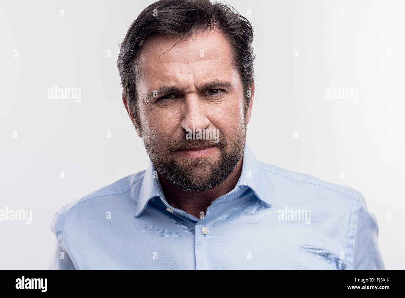 Bearded dark-haired man feeling angry after some arguments at work Stock Photo