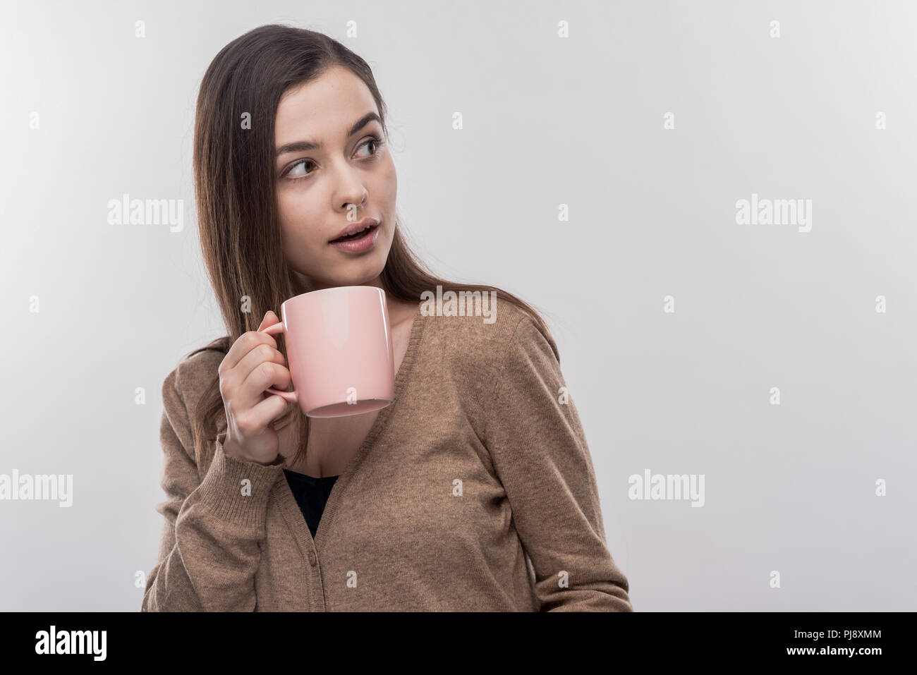 Dark-haired female intern having rest while drinking coffee during lunch time Stock Photo