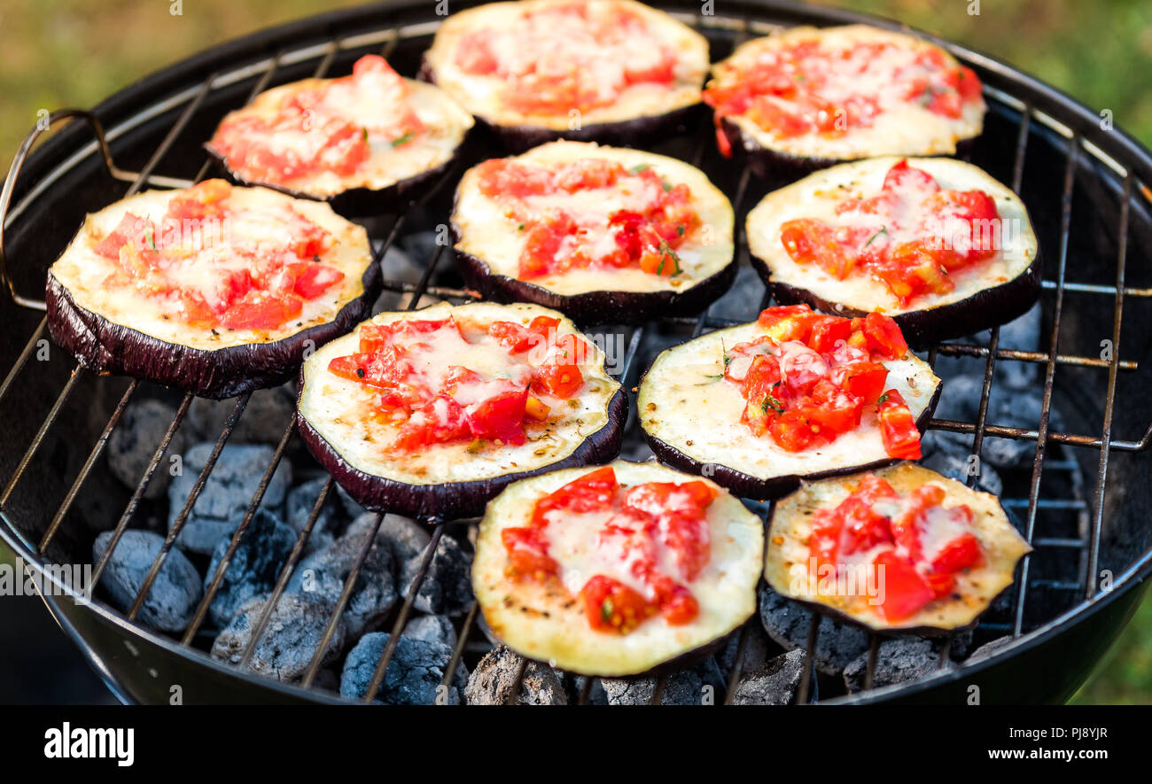 Eggplant with tomato and parmesan cheese on BBQ vegan grill. Grilling  vegetables as delicious vegetarian or vegan barbecue picnic over hot coals.  Ital Stock Photo - Alamy