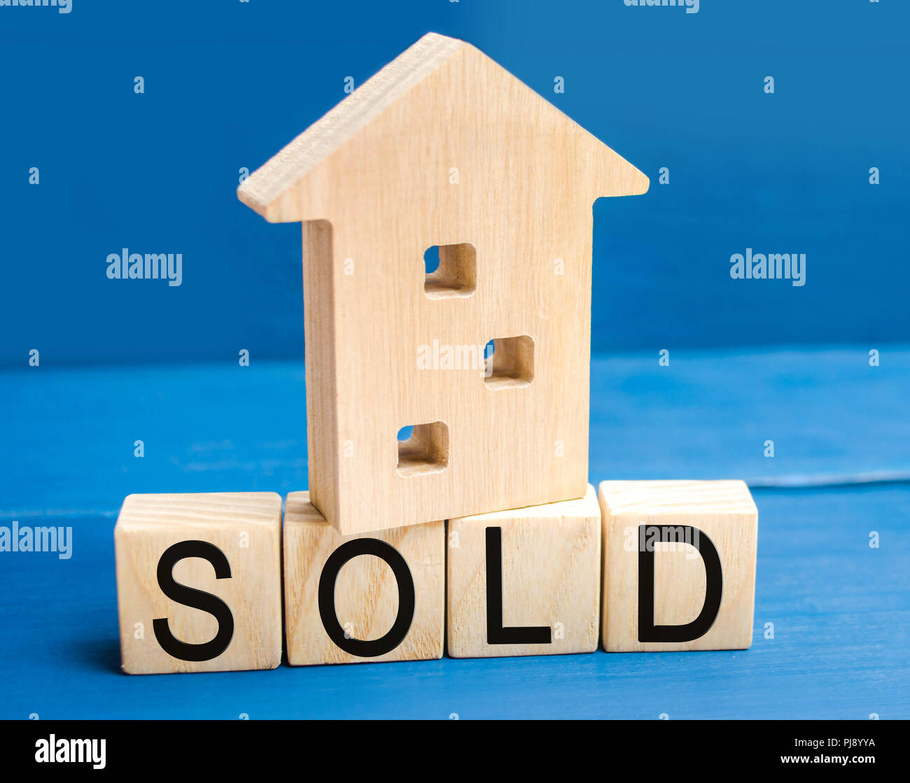 wooden house on a blue background with the inscription sold. sale of
