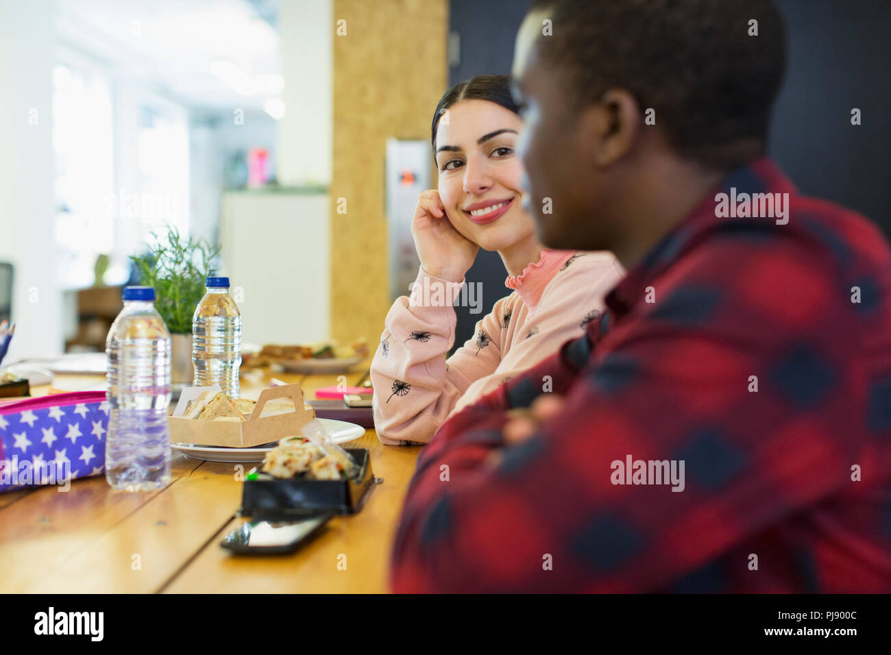 Smiling businesswoman listening to businessman, eating lunch in office Stock Photo