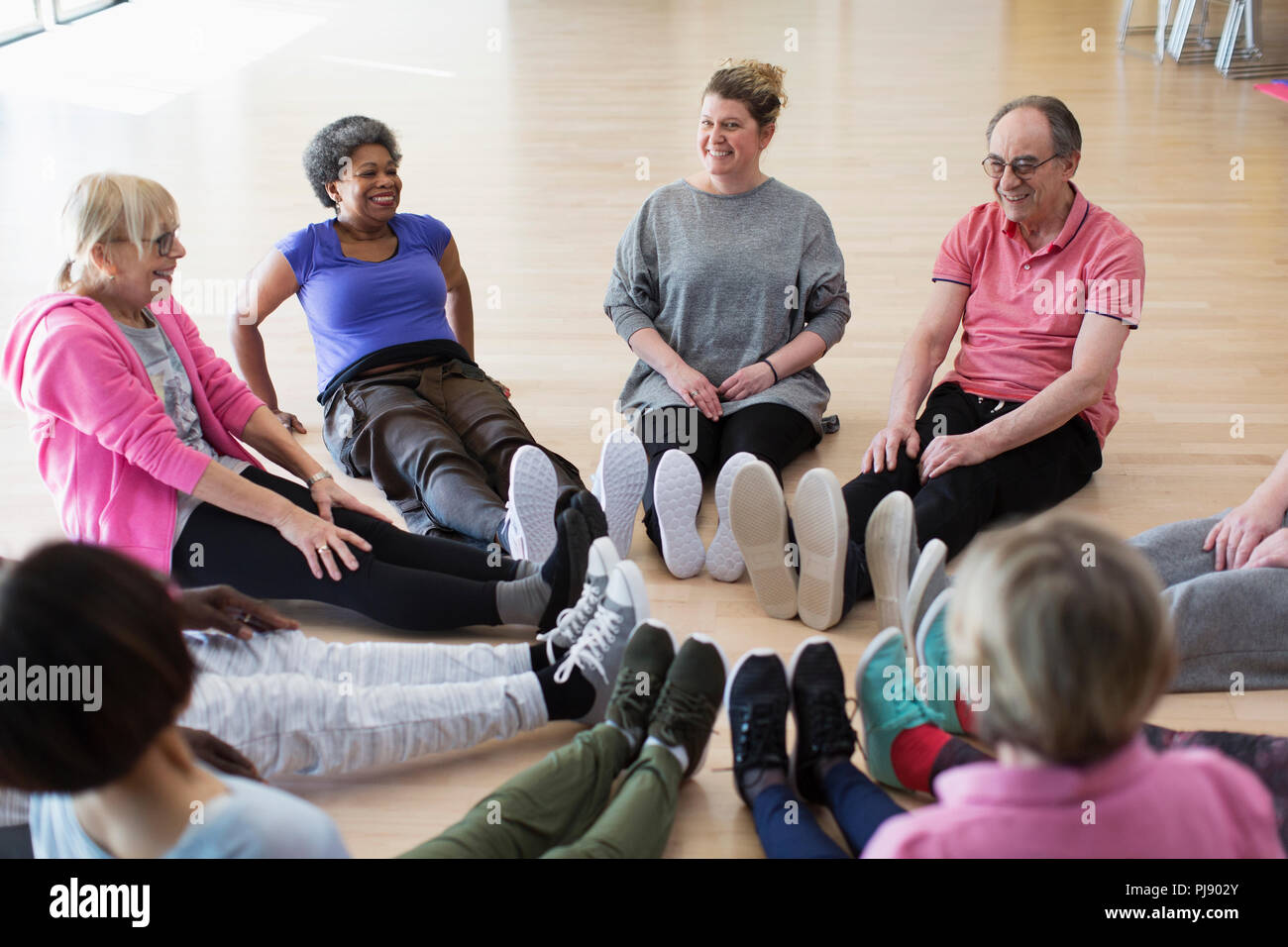 Instructor and active seniors stretching legs in circle in exercise class Stock Photo