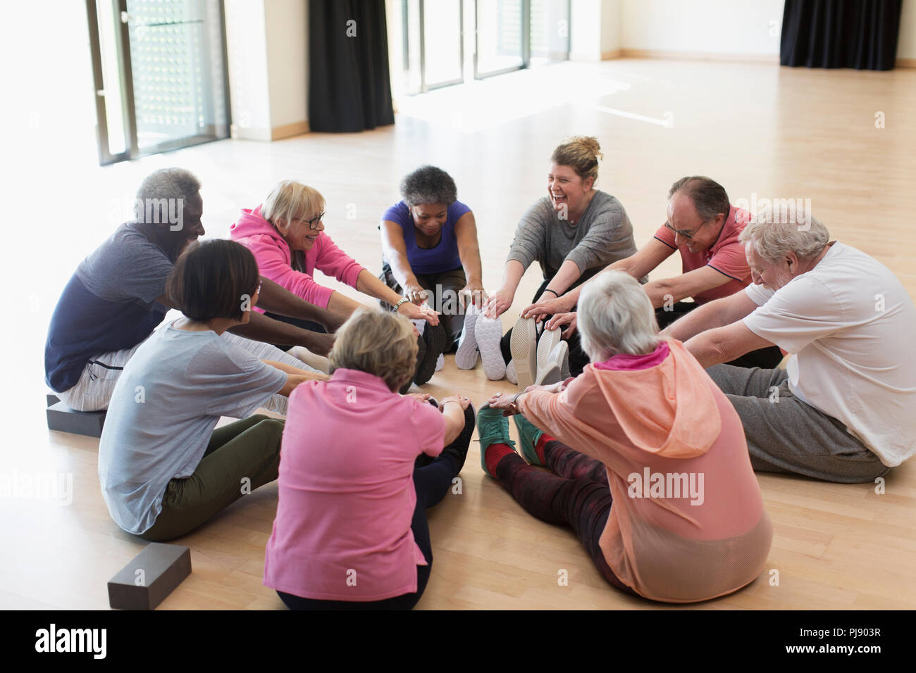 Active seniors exercising, stretching legs in circle Stock Photo