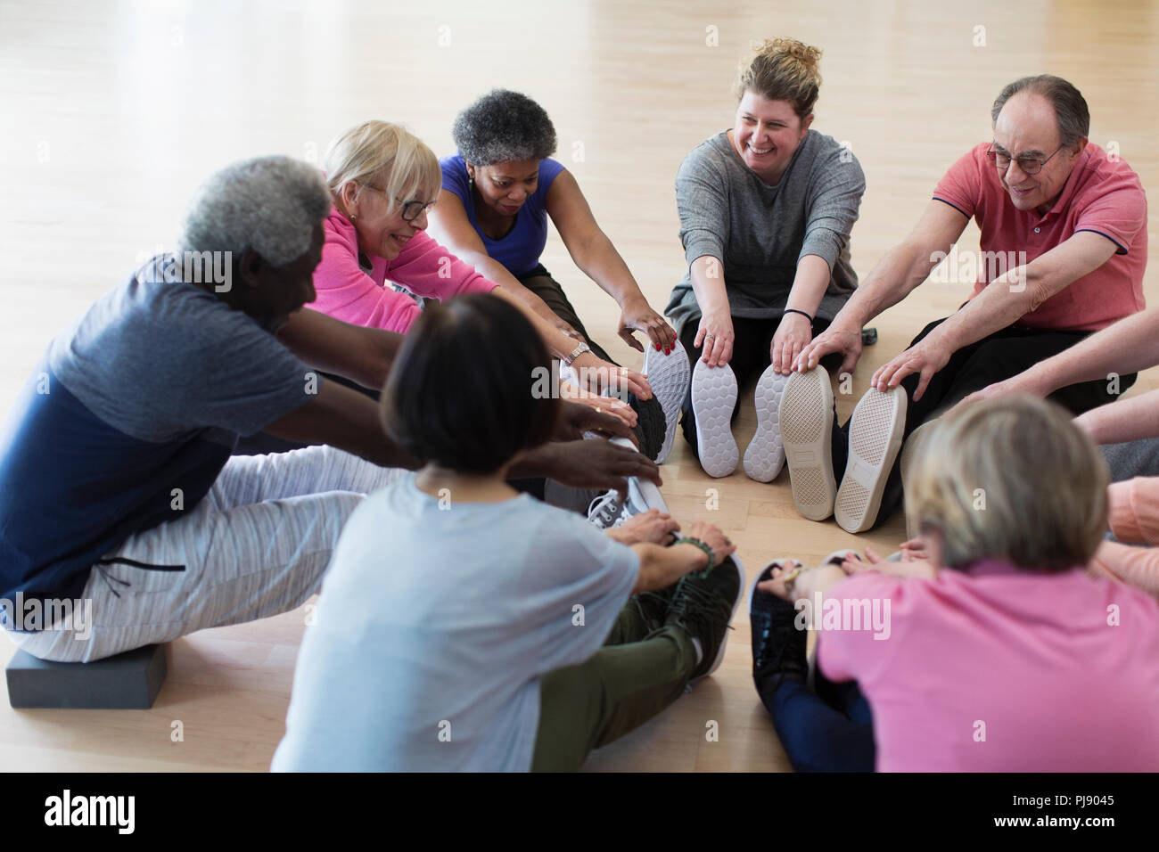 Smiling active seniors stretching legs in circle Stock Photo