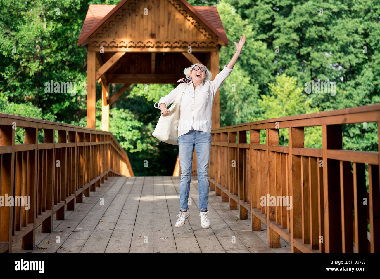 Happy retired woman jumping while enjoying nice eco tourism Stock Photo