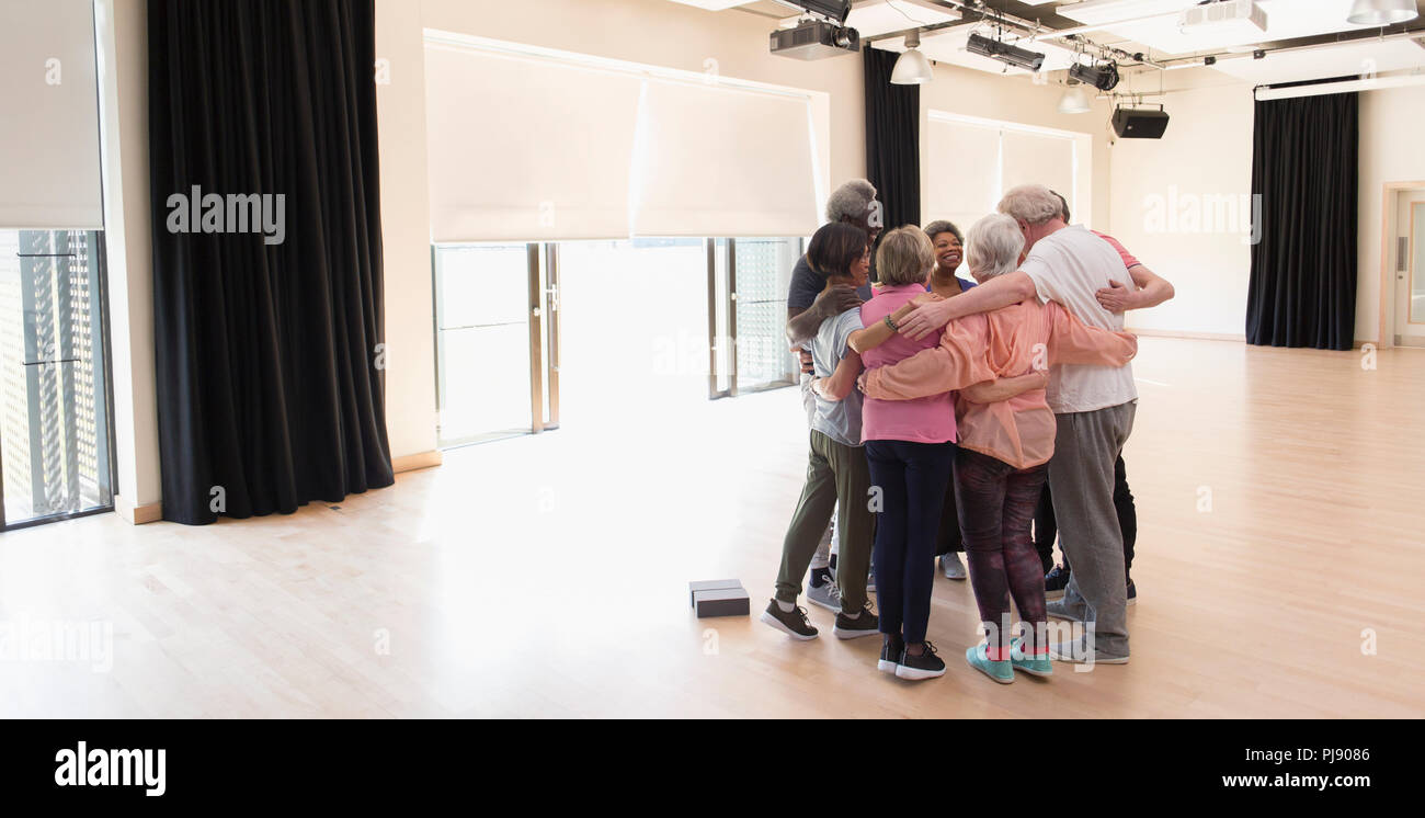 Active seniors bonding, hugging in circle in exercise studio Stock Photo