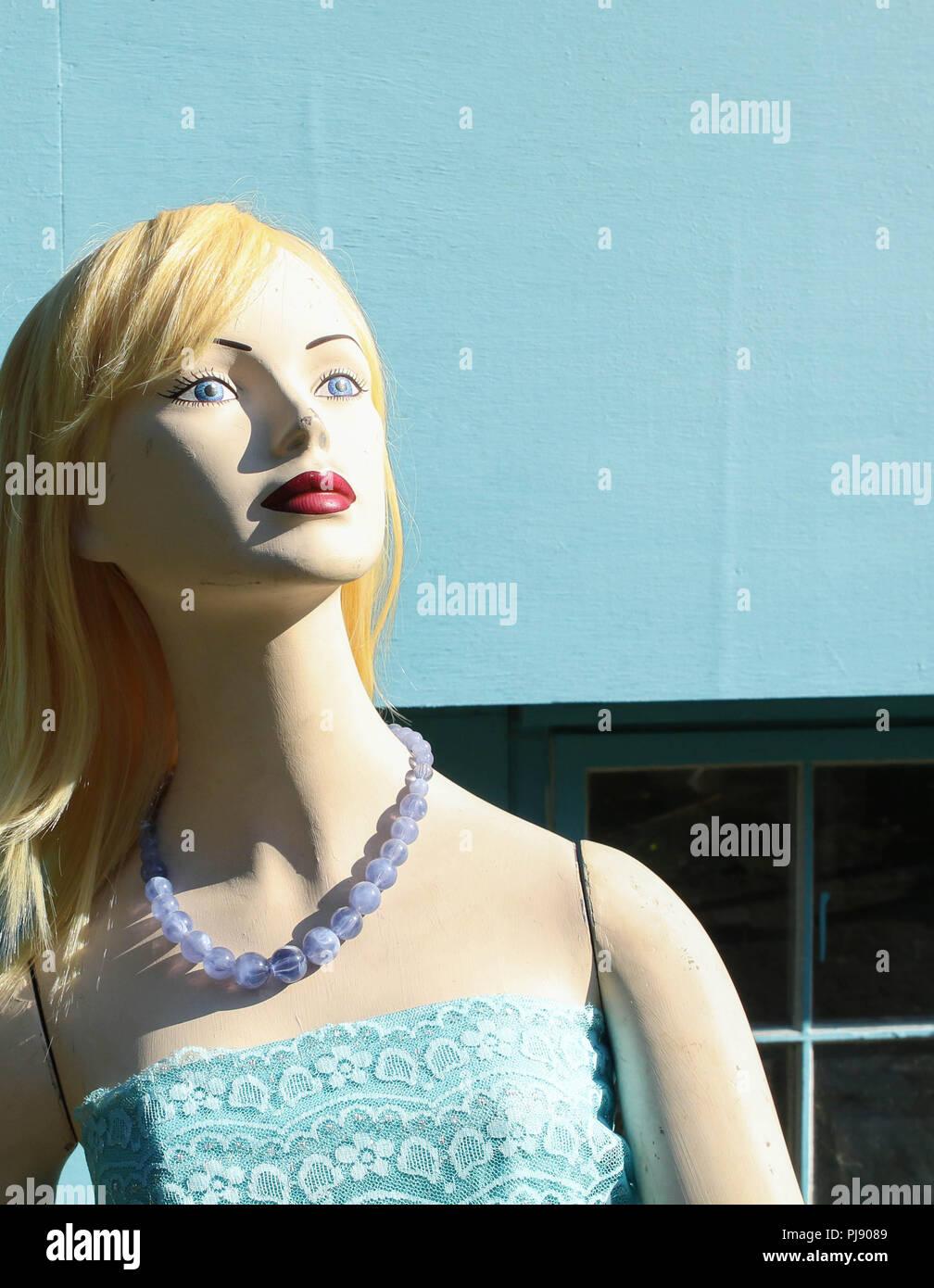 Head and shoulders of lady mannequin standing in front of blue building. Stock Photo