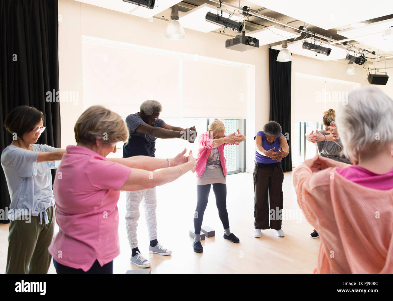 Active seniors exercising, stretching arms and back in circle Stock Photo