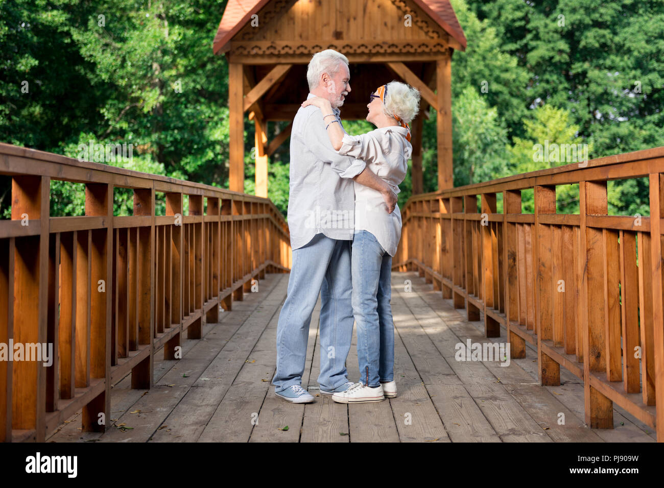 Happy good-looking pensioners dancing in the middle of bridge Stock Photo