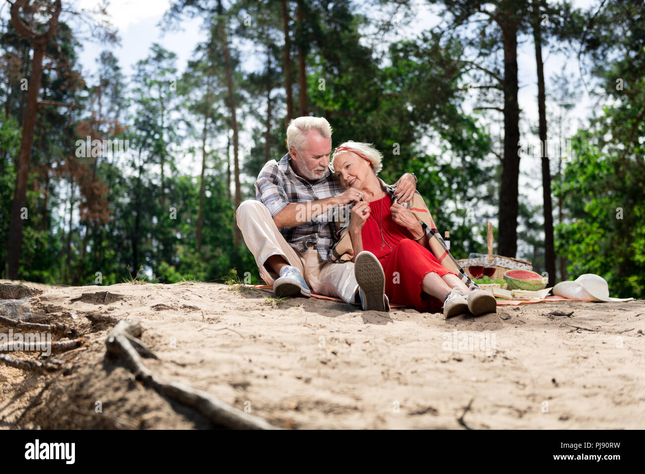 Beaming aged woman leaning on shoulders of her strong husband Stock Photo