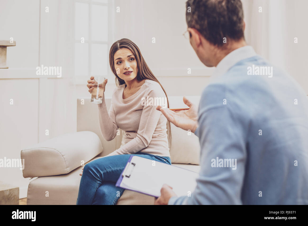 Depressed young woman drinking water Stock Photo Alamy