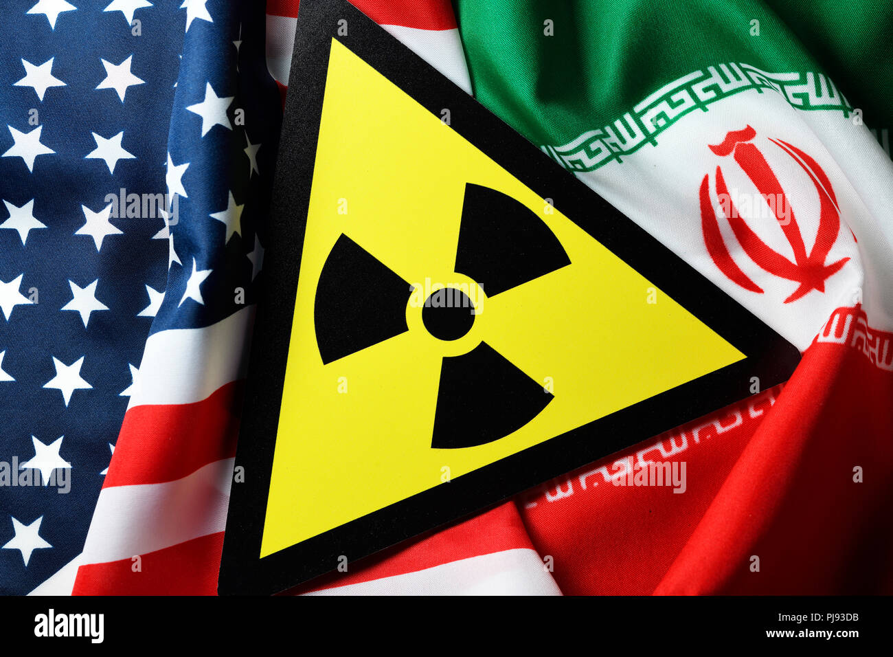 Flags of the USA and Iran and radioactivity warning, Iranian nuclear agreement, Fahnen von USA und Iran und Radioaktivität-Warnschild, iranisches Atom Stock Photo