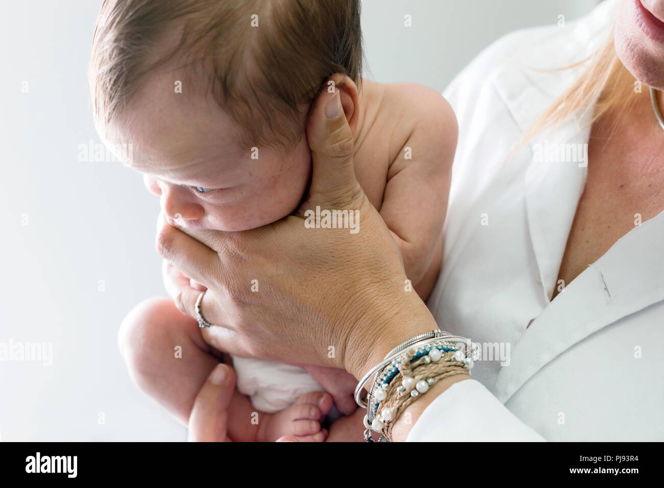 Newborn baby boy looking aside kept by the nurse in white uniform Stock Photo