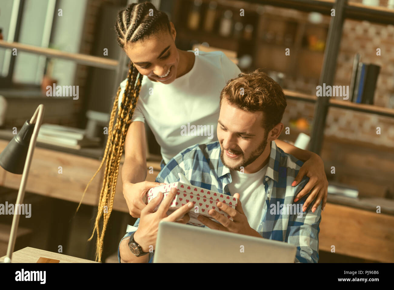 Thoughtful young lady surprising soulmate with present Stock Photo