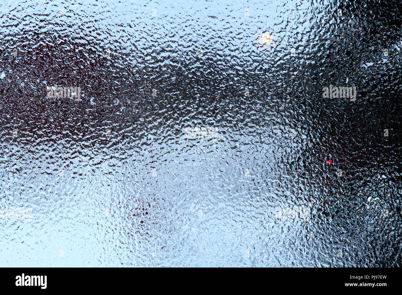 Frosty, freezing rain on a window. Pattern, texture of spot. Garden in the  background Stock Photo - Alamy
