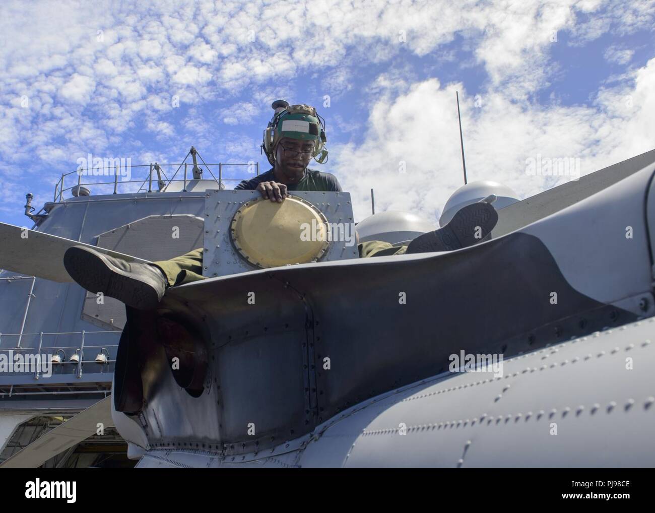 SEA OF JAPAN (July 8, 2018) Aviation Electronics Technician 2nd Class Shyhiem Rhodes, from Rockport, New York, performs maintenance on a MH-60R Sea Hawk helicopter, assigned to the “Warlords” of Helicopter Maritime Strike Squadron (HSM) 51 on the flight deck of the Ticonderoga-class guided-missile cruiser USS Antietam (CG 54). Antietam is on patrol in the U.S. 7th Fleet area of operation supporting security and stability in the Indo-Pacific region. Stock Photo