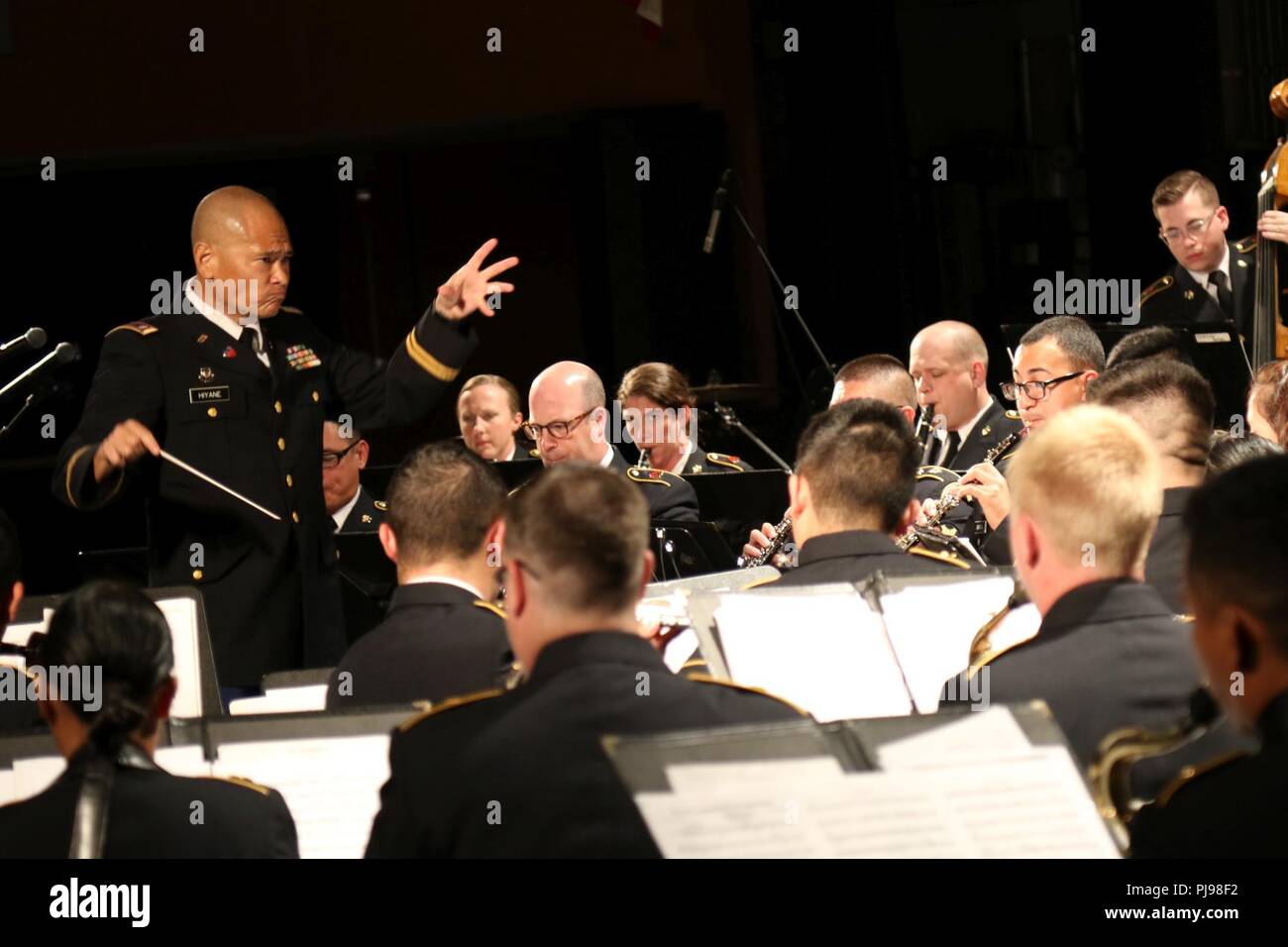 Chief Warrant Officer Four Curtis Hiyane, Commander of the 111th Army Band, conducts a song during the joint concert of the 111th Army Band and 234th Army Band at Astoria High School in Astoria, Oregon, July 7, 2018. The concert is the second collaboration between the 111th Army Band and the 234th Army Band with efforts to display the results of their training in a live setting. Stock Photo