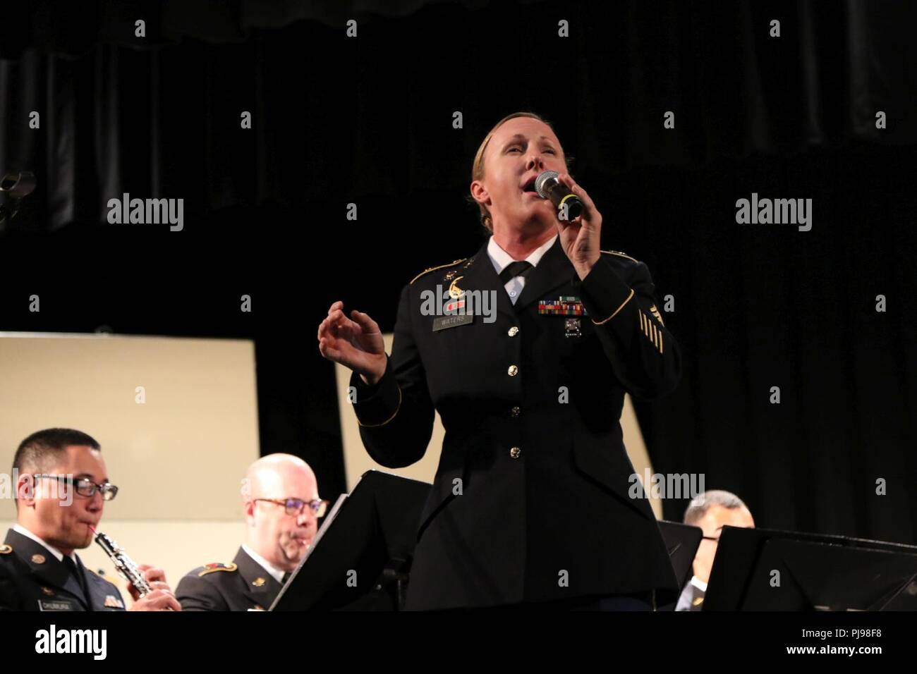 Staff Sgt. Krysta Waters of the 111th Army Band sings passionately in her performance during the joint concert of the 111th Army Band and the 234th Army Band at Astoria High School in Astoria, Oregon, July 7, 2018.  The concert is the second collaboration between the 111th Army Band and the 234th Army Band with efforts to display the results of their training in a live setting. Stock Photo