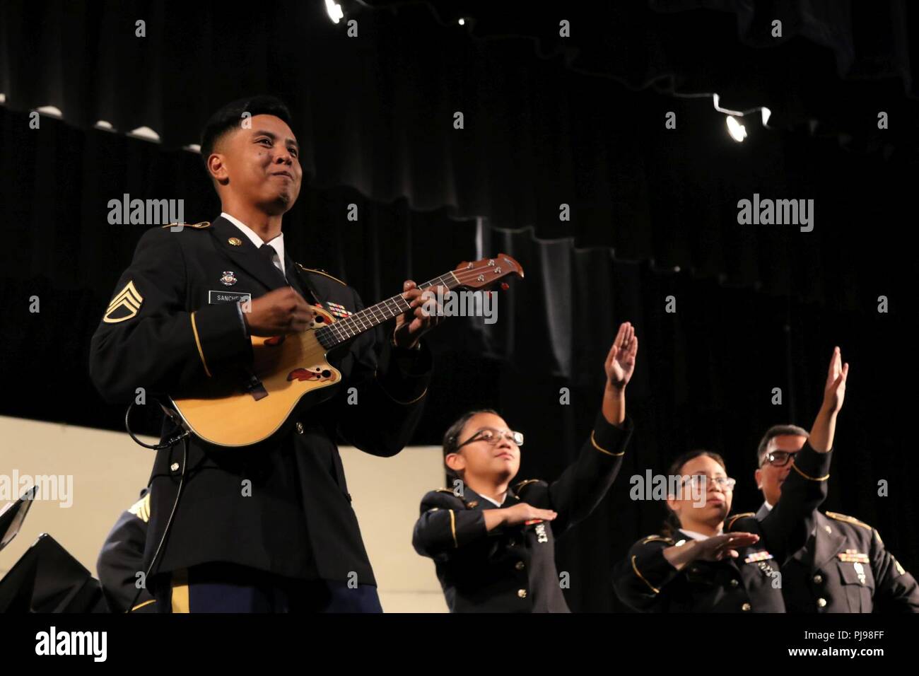 Staff Sgt. Bryan Sanchez performs a ukulele solo during the joint concert of the 111th Army Band and the 234th Army Band at Astoria High School in Astoria, Oregon, July 7, 2018. The concert is the second collaboration between the 111th Army Band and the 234th Army Band with efforts to display the results of their training in a live setting. Stock Photo