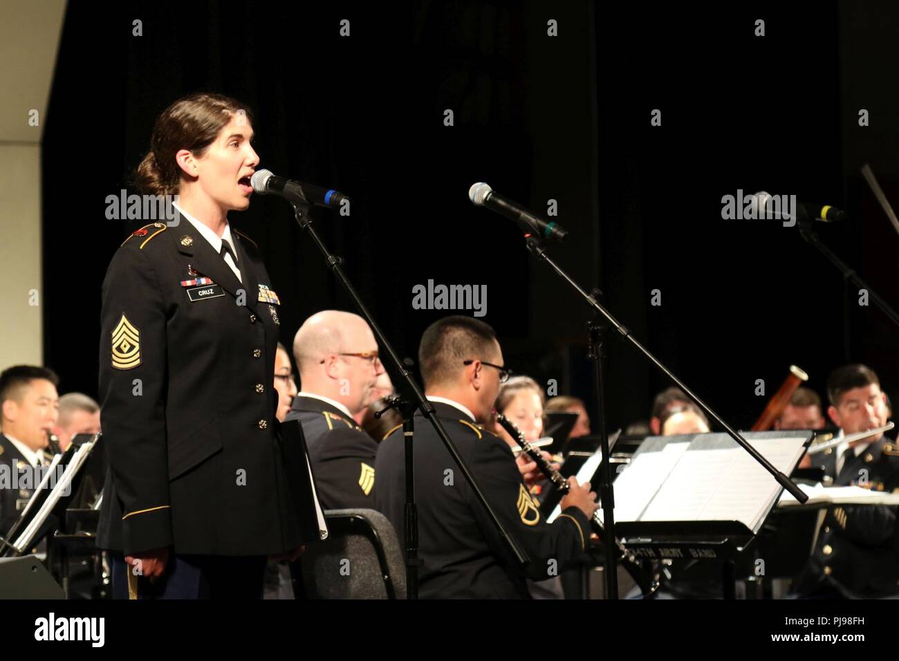 1st Sgt. Tasha Cruz of the 234th Army Band performs the Service Song Medley in honor of the military veterans in the crowd during the joint concert of the 111th Army Band and the 234th Army Band in Astoria High School in Astoria, Oregon, July 7, 2018. The concert is the second collaboration between the 111th Army Band and the 234th Army Band with efforts to display the results of their training in a live setting. Stock Photo