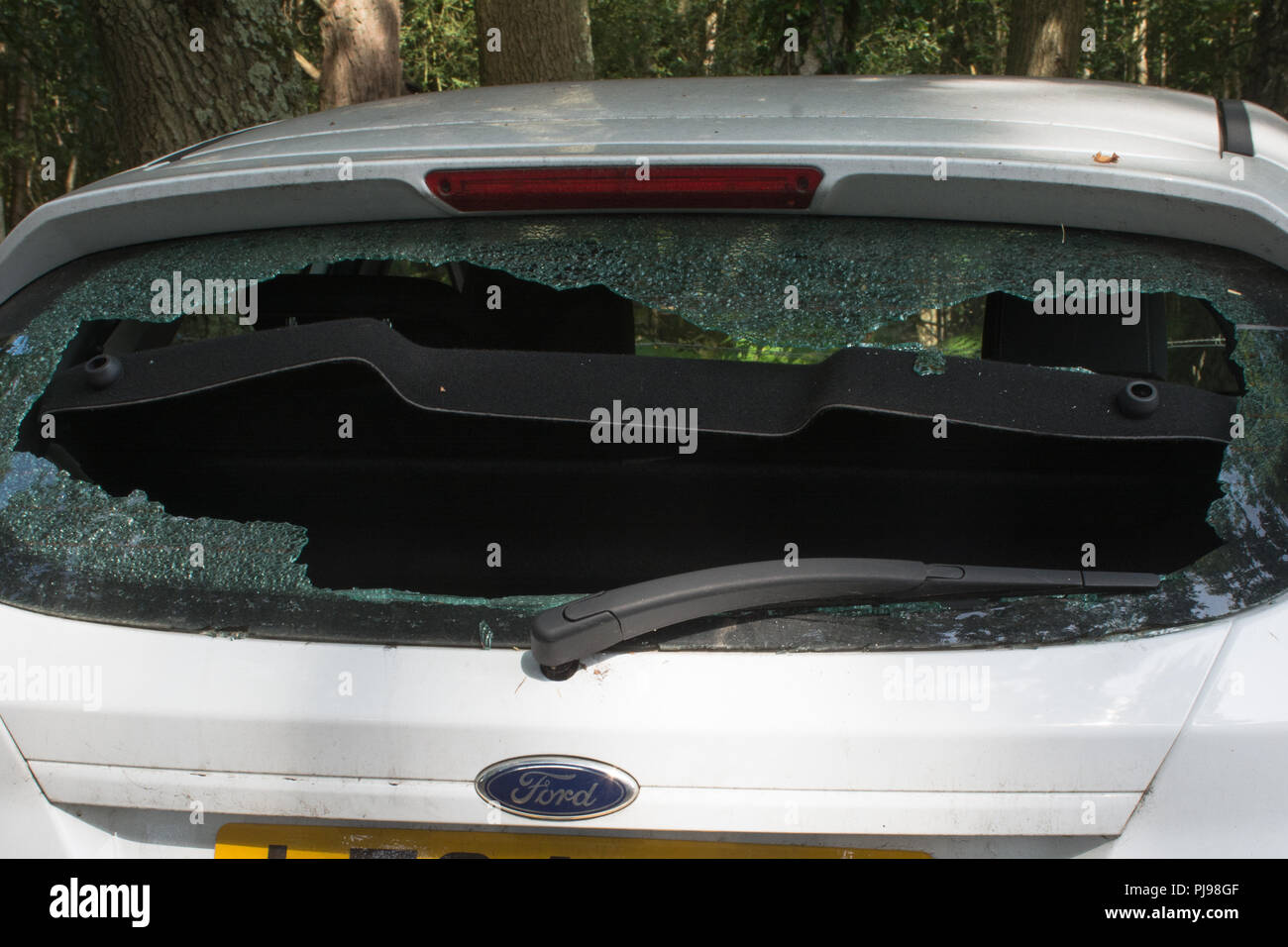 White ford fiesta car with smashed rear windscreen in a woodland car park Stock Photo