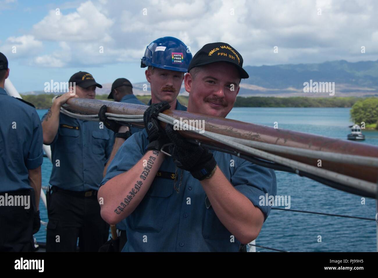 PEARL HARBOR (July 9, 2018) Ordinary Seaman (OS)  Andrew Henderson (rear) and Leading Seaman (LS) Josh Reves (front) stow the “jack staff” as the Royal Canadian Navy frigate HMCS Vancouver (FFH 331) departs Pearl Harbor for the at sea phase of the Rim of the Pacific exercise (RIMPAC), July 9. Twenty-five nations, 46 ships, five submarines, about 200 aircraft and 25,000 personnel are participating in RIMPAC from June 27 to Aug. 2 in and around the Hawaiian Islands and Southern California. The world’s largest international maritime exercise, RIMPAC provides a unique training opportunity while fo Stock Photo