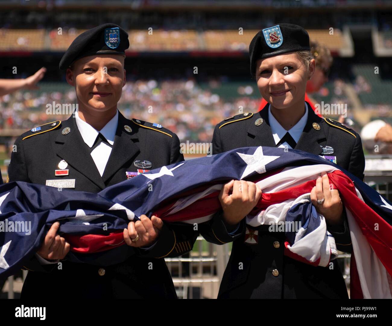 1st Sgt. Katie Blackwell and Staff Sgt. Ashley Meraz prepare to raise the American flag during the 2018 Minnesota Twins Armed Forces Appreciation Day. Blackwell and Meraz are both Purple Heart recipients from the Minnesota Army National Guard. Blackwell received the Purple Heart when she was wounded after her scout vehicle struck an improvised explosive device May 29, 2006, in Baghdad, Iraq. Meraz was wounded after her vehicle drove over a pressure plate improvised explosive device near Forward Operating Base Leatherneck in Afghanistan, October 7, 2009. Her driver, Spc. George Cauley, was kill Stock Photo