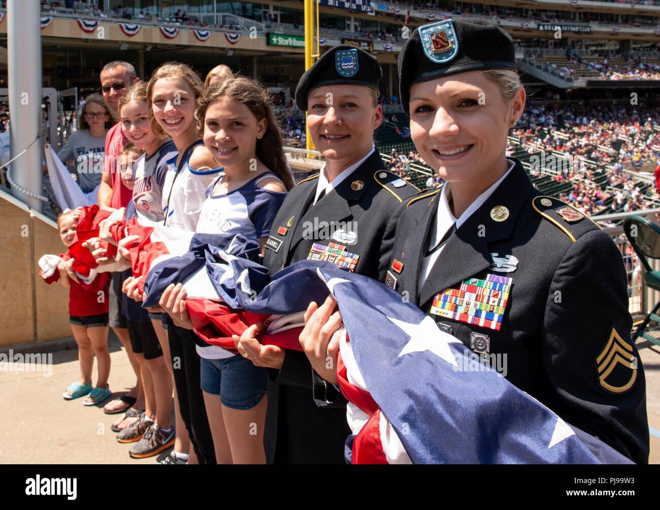 1st Sgt. Katie Blackwell and Staff Sgt. Ashley Meraz prepare to raise the American flag during the 2018 Minnesota Twins Armed Forces Appreciation Day. Blackwell and Meraz are both Purple Heart recipients from the Minnesota Army National Guard. Blackwell received the Purple Heart when she was wounded after her scout vehicle struck an improvised explosive device May 29, 2006, in Baghdad, Iraq. Meraz was wounded after her vehicle drove over a pressure plate improvised explosive device near Forward Operating Base Leatherneck in Afghanistan, October 7, 2009. Her driver, Spc. George Cauley, was kill Stock Photo