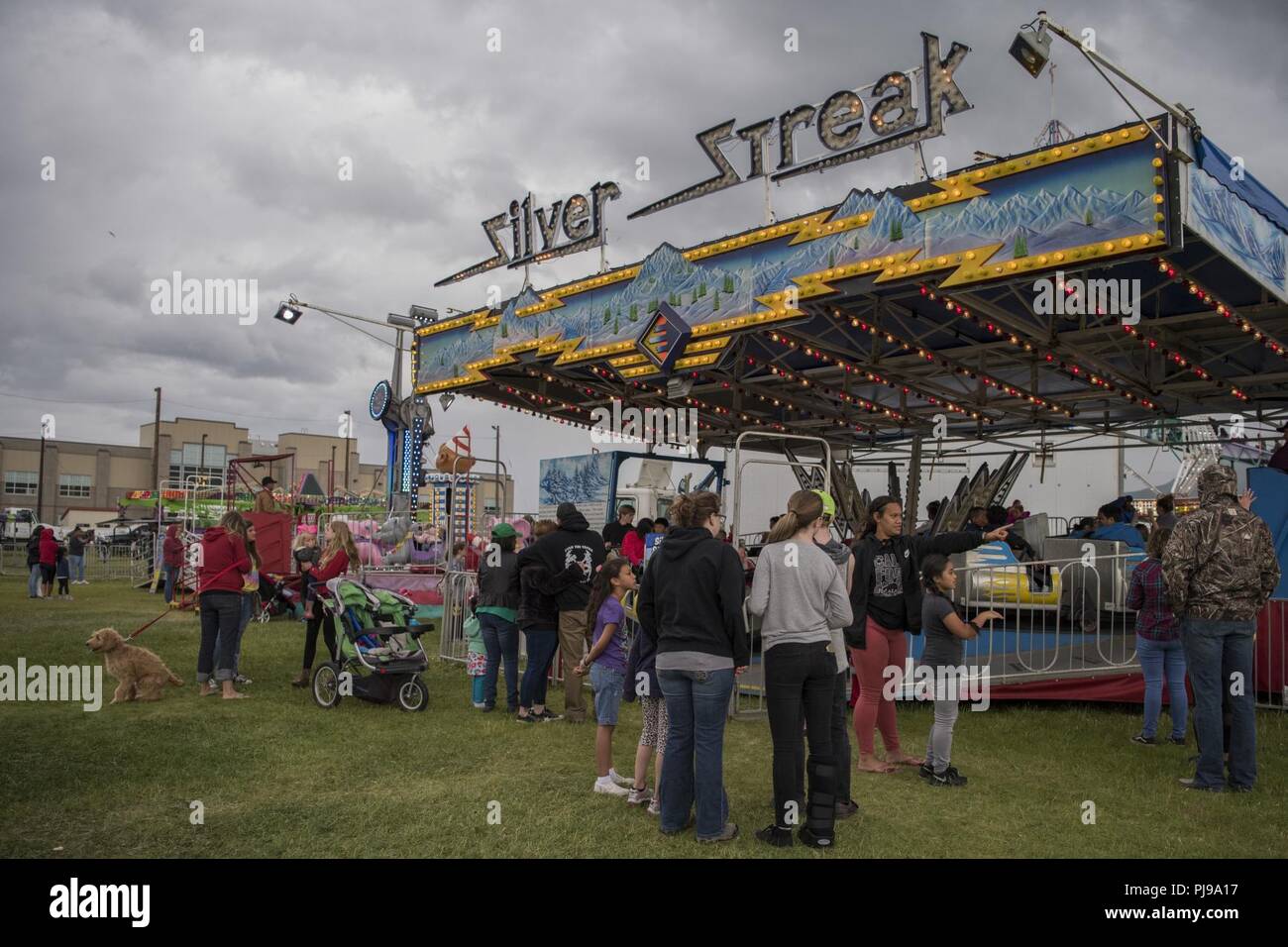 Participants wait in line for an amusement ride during the 3rd annual Summer Fest hosted by the 673d Force Support Squadron at Joint Base Elmendorf-Richardson, Alaska, July 8, 2018. The event was open to anyone with base access and offered free activities such as carnival rides, a petting zoo, face painting, a bungee trampoline, and carnival games. Stock Photo