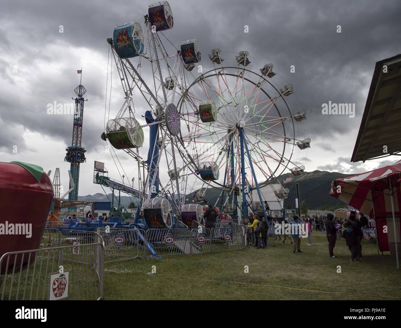 Participants wait in line for amusement rides and games offered during the 3rd annual Summer Fest hosted by the 673d Force Support Squadron at Joint Base Elmendorf-Richardson, Alaska, July 8, 2018. The event was open to anyone with base access and offered free activities such as carnival rides, a petting zoo, face painting, a bungee trampoline, and carnival games. Stock Photo