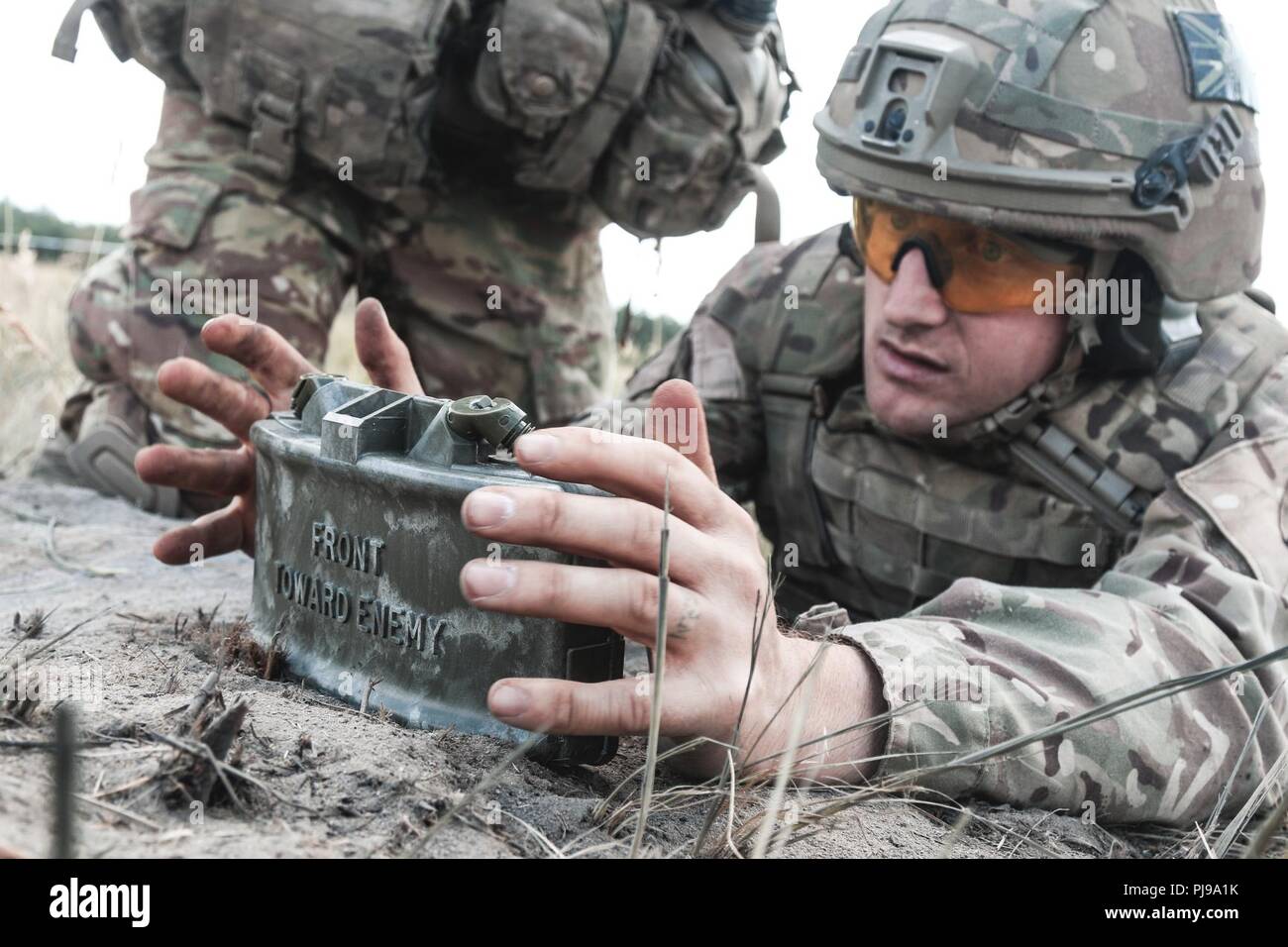 U.K. Sgt. Rob Veasey, a troop sergeant with 1st The Queen's Dragoon Guards, emplaces M18A1 Claymore mine during a multinational claymore training exercise with Battle Group Poland at Bemowo Piskie Training Area, Poland on July 10, 2018. Battle Group Poland is a unique, multinational coalition of U.S., U.K., Croatian and Romanian Soldiers who serve with the Polish 15th Mechanized Brigade as a deterrence force in support of NATO’s Enhanced Forward Presence. Stock Photo