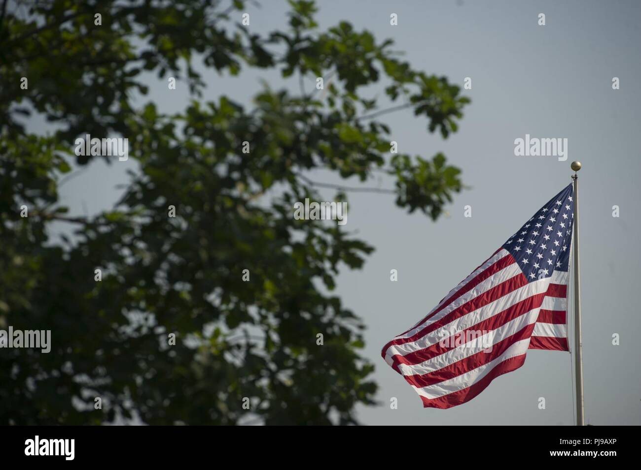 An American flag waves over the parade ground as Joint Base Anacostia-Bolling celebrates its 100th Anniversary Jul 3, 2018. Bolling Field was officially dedicated on 1 July, 1918, after the property was purchased by the War Department and turned over to the Aviation Section of the Signal Corps to serve as the primary aviation facility for the capital city. This new military property was appropriately named for Colonel Raynal C. Bolling, an early vanguard in the quest for Army airmanship. Stock Photo
