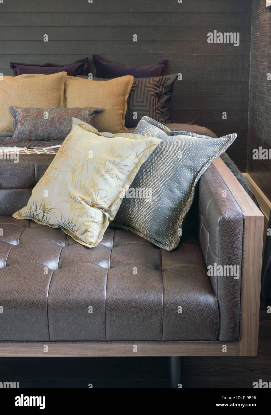 Brown leather sofa with pillows at end of bed in bedroom Stock Photo