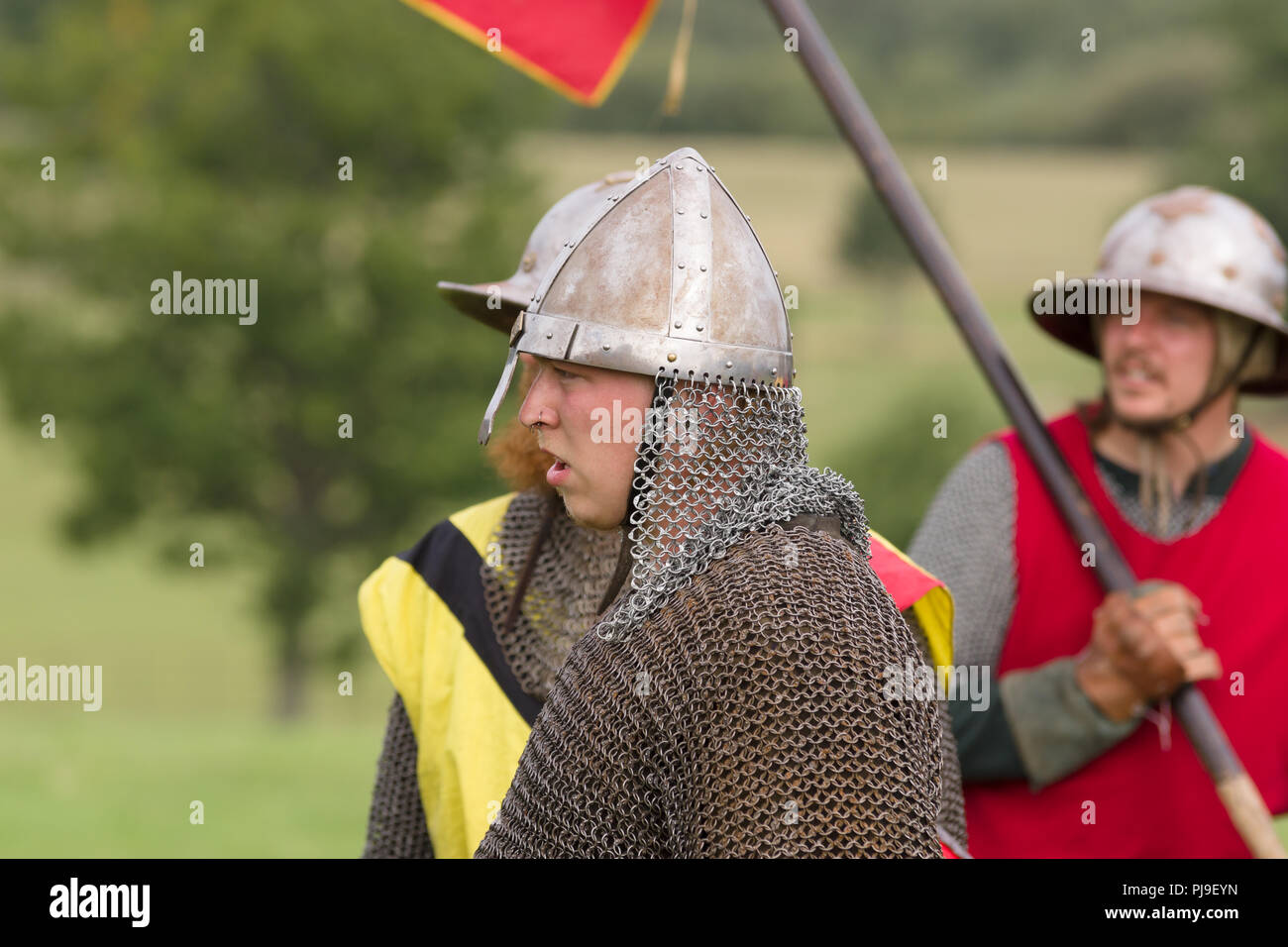 Medieval battle re-enactment with men wearing a spangenhelm helmet and chain mail aventail or camail to protect the neck Stock Photo