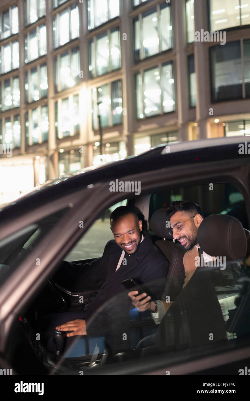 Businessman showing smart phone to driver in crowdsourced taxi Stock Photo