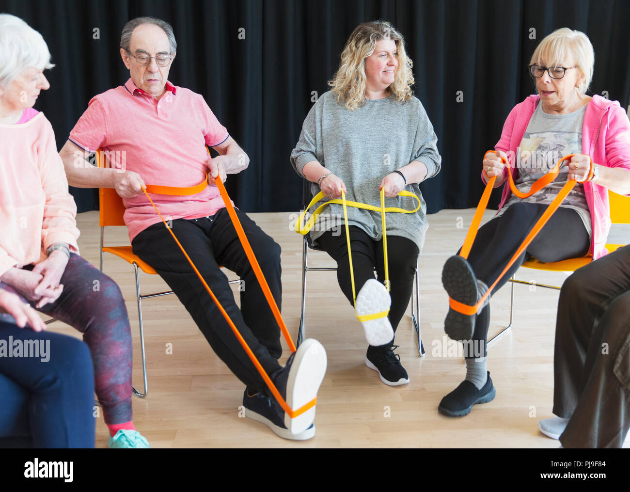 Active seniors exercising in circle, using straps to stretch legs Stock Photo