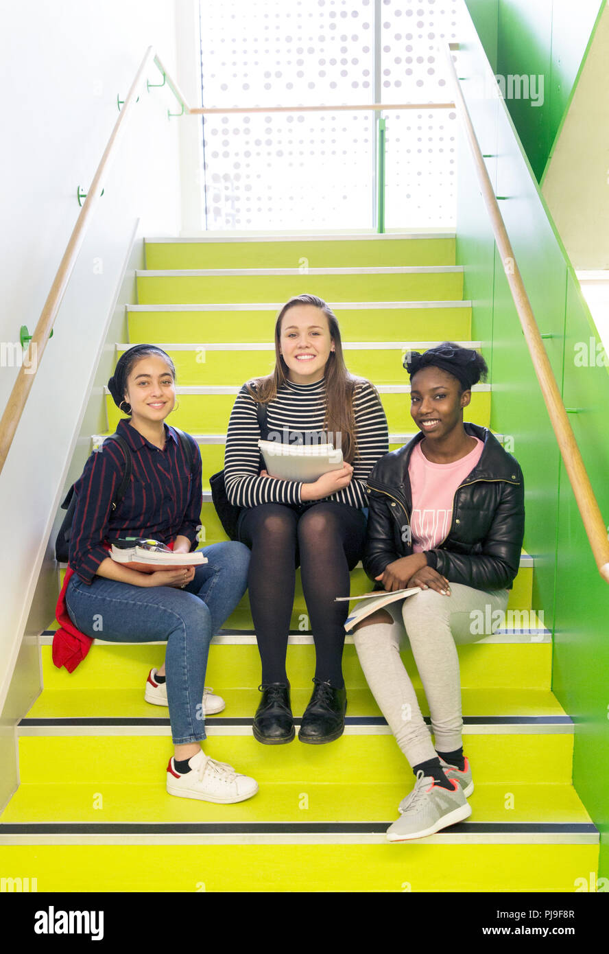 Portrait smiling, confident high school girls sitting on stairs Stock Photo