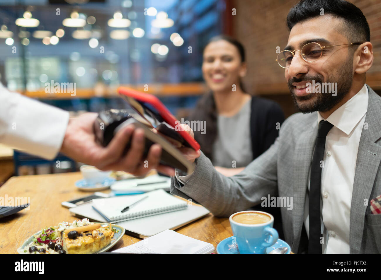 Businessman paying with smart phone contactless payment in cafe Stock Photo