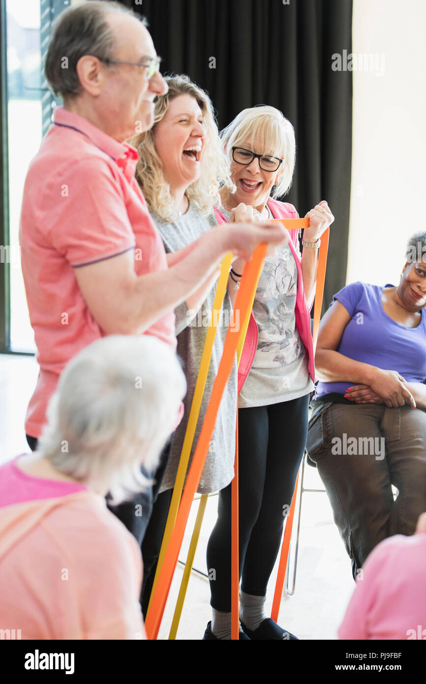 Smiling active seniors and instructor stretching, exercising with straps Stock Photo