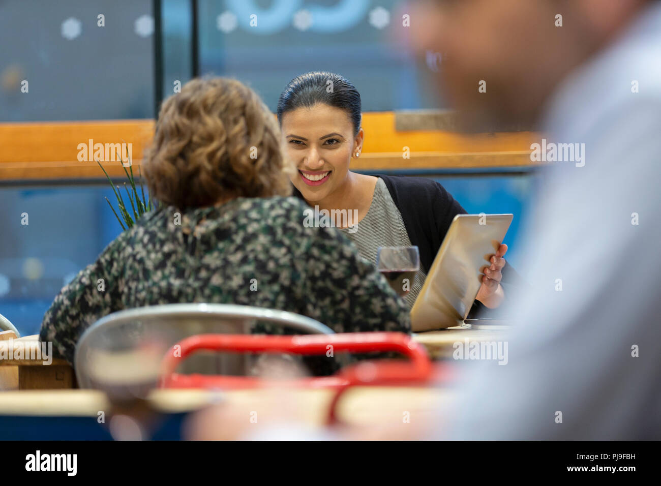 Businesswomen with digital tablet talking, working in cafe Stock Photo